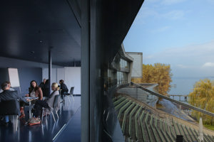 Workshopteilnehmer:innen sitzen in Gruppen in der Blauen Lounge mit Blick auf die Tribüne und den Bodensee