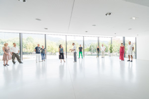 Workshopteilnehmer:innen stehen verteilt im weißen tageslichtdurchfluteten Saal Panorama im Festspielhaus Bregenz