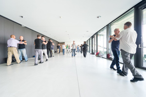 Tanzpaare in der weißen Seegalerie mit langer Glasfront und Ausgängen auf die Seetribüne