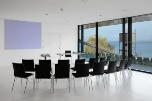 © Anja Koehler Zwei Reihen schwarze Stühle vor einem Vortragenden-Pult und Beamer in der weißen Seegalerie mit Seeblick © Anja Koehler
