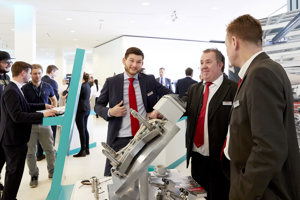 Kongressteilnehmer im Anzügn vor Ausstellungskojen im hellen Foyer des Festspielhauses Bregenz