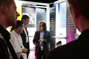 Kongressteilnehmer:innen informieren sich in der Fachausstellung an einem Stand auf der Werkstattbühne im Festspielhaus