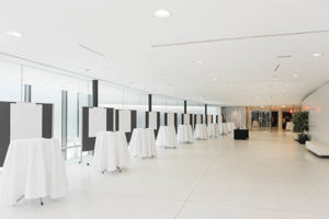 Stehtisch-Reihe mit weißen Tischtüchern und Flipcharts vor der langen Glasfront im Parkstudio des Festspielhauses Bregenz