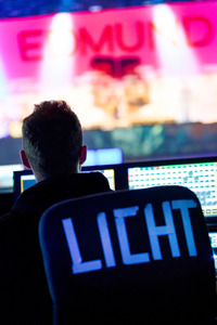 Ein Lichttechniker sitzt vor einem Technikpult bei einem Stehkonzert