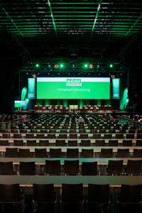 Leere Parlamentbetischung vor einer großen Bühne und einer sehr großen Leinwand