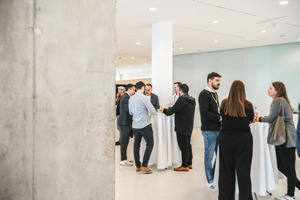 Teilnehehmer:innen unterhalten sich an Stehtischen im hellen Foyer 2 im Festspielhaus Bregenz