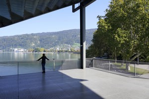 Ein Frau steht am Geländer der Parkstudio-Terrasse des Festspielhauses und schaut auf den Bodensee.